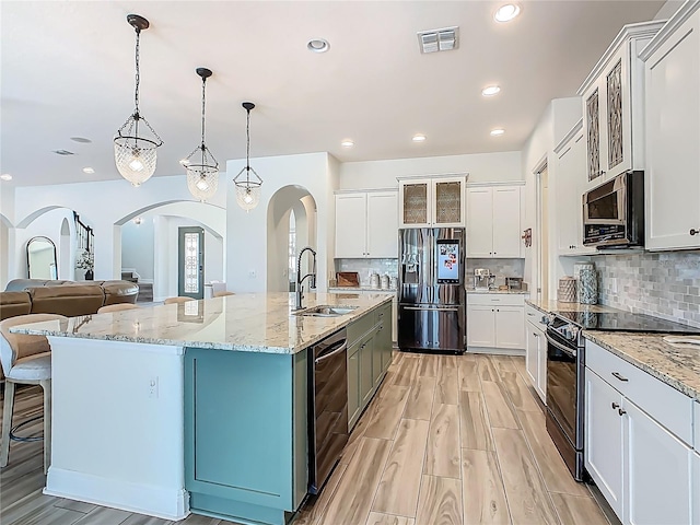 1211 Terralago Way, Kissimmee, FL 34746 - kitchen featuring black appliances, a sink, arched walkways, decorative backsplash, and white cabinets