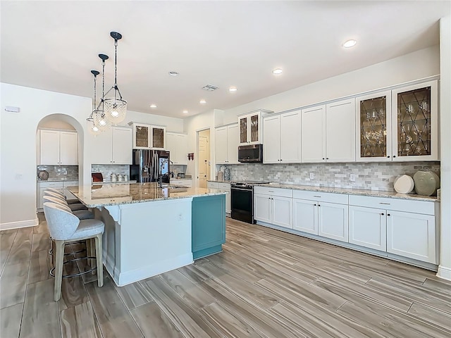 1211 Terralago Way, Kissimmee, FL 34746 - kitchen with range, black fridge with ice dispenser, stainless steel microwave, a sink, and light wood finished floors