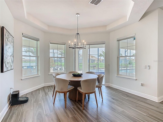 1211 Terralago Way, Kissimmee, FL 34746 - dining area featuring a raised ceiling, a chandelier, wood finish floors, and baseboards