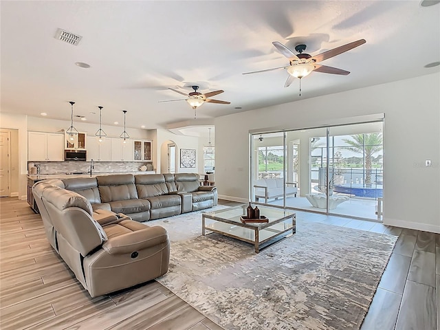 1211 Terralago Way, Kissimmee, FL 34746 - living room featuring a ceiling fan, baseboards, arched walkways, light wood-style flooring, and recessed lighting