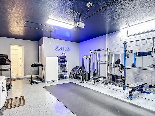 1211 Terralago Way, Kissimmee, FL 34746 - exercise room with a garage, a textured ceiling, concrete block wall, and baseboards