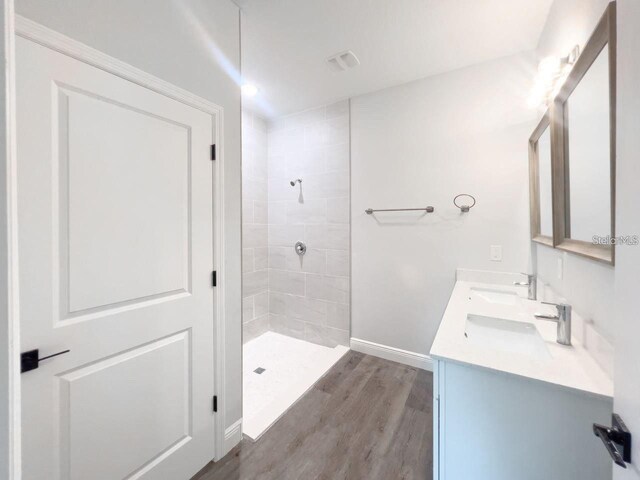 17381 Tyler Ave, Port Charlotte, FL 33948 - full bath featuring a tile shower, wood finished floors, double vanity, and baseboards