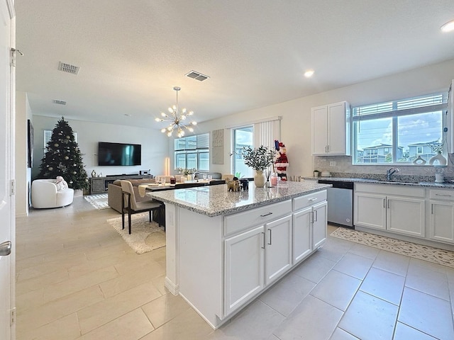 895 Overpool Ave, Davenport, FL 33896 - kitchen with stainless steel dishwasher, a chandelier, a kitchen island, light stone countertops, and white cabinets
