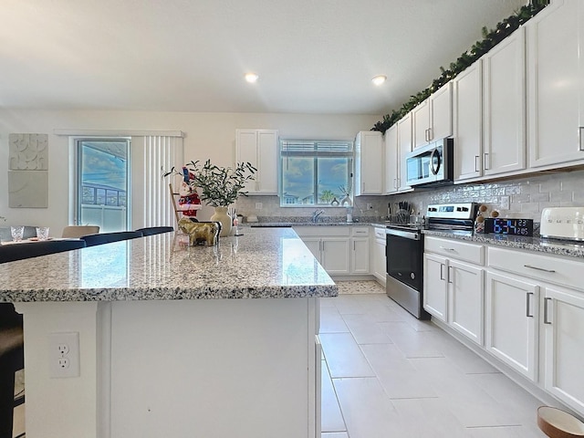 895 Overpool Ave, Davenport, FL 33896 - kitchen featuring stainless steel appliances, backsplash, a kitchen island, light stone countertops, and a breakfast bar area