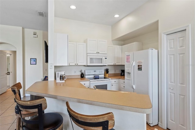 833 Brunello Dr, Davenport, FL 33897 - kitchen with white appliances, a peninsula, light countertops, light tile patterned floors, and white cabinets