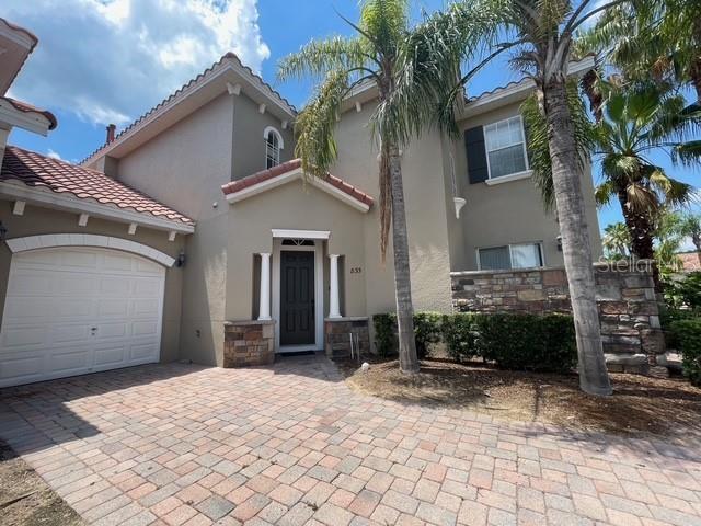 833 Brunello Dr, Davenport, FL 33897 - mediterranean / spanish-style house with stucco siding, a garage, stone siding, a tile roof, and decorative driveway