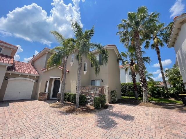 833 Brunello Dr, Davenport, FL 33897 - mediterranean / spanish house featuring stucco siding, an attached garage, decorative driveway, a tile roof, and stone siding