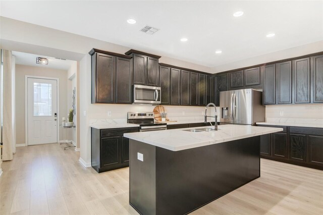 8042 Glenlloyd Ave, Winter Garden, FL 34787 - kitchen with appliances with stainless steel finishes, a sink, light stone countertops, light wood-style floors, and a kitchen island with sink