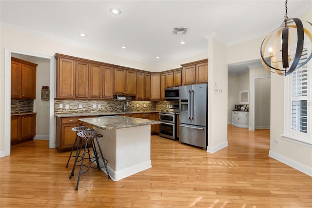 3349 Schoolhouse Rd, Harmony, FL 34773 - kitchen featuring appliances with stainless steel finishes, tasteful backsplash, brown cabinetry, a kitchen bar, and ornamental molding
