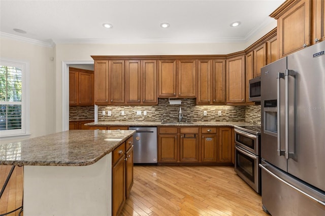 3349 Schoolhouse Rd, Harmony, FL 34773 - kitchen featuring stainless steel appliances, a sink, brown cabinetry, crown molding, and light wood-style floors