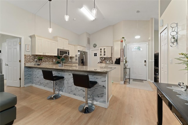 2507 Talega Dr, Saint Cloud, FL 34772 - kitchen with stainless steel appliances, high vaulted ceiling, a kitchen breakfast bar, a peninsula, and light stone counters