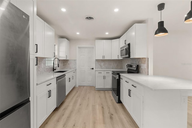 1842 Puritan Ave, Winter Park, FL 32792 - kitchen featuring stainless steel appliances, a sink, light wood finished floors, white cabinetry, and backsplash