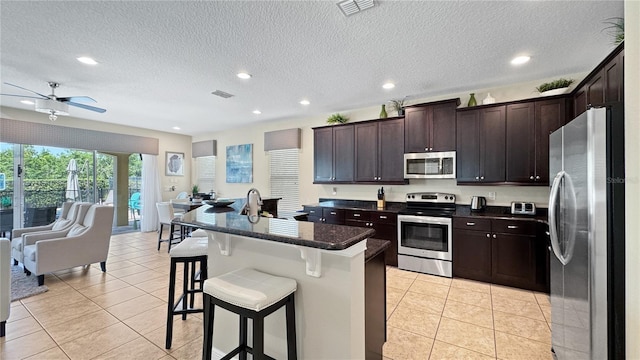 1228 Castle Pines Ct, Reunion, FL 34747 - kitchen with stainless steel appliances, open floor plan, a kitchen breakfast bar, recessed lighting, and dark brown cabinets