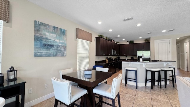 1228 Castle Pines Ct, Reunion, FL 34747 - dining room with arched walkways, recessed lighting, baseboards, a textured ceiling, and light tile patterned flooring