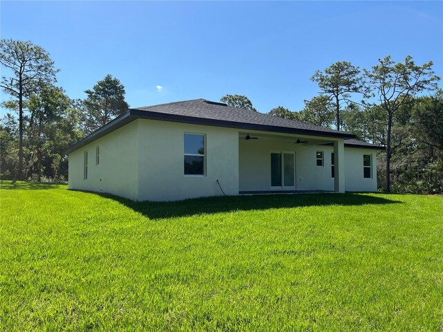 814 Gator Ln, Deltona, FL 32738 - back of property with stucco siding, ceiling fan, and a yard