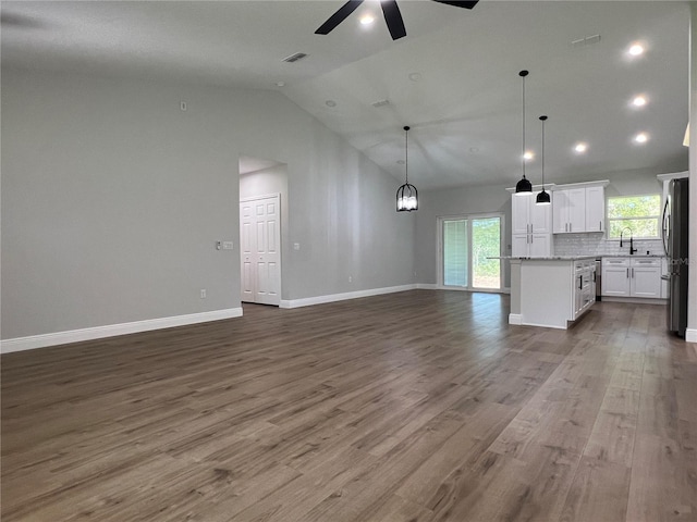 814 Gator Ln, Deltona, FL 32738 - unfurnished living room with ceiling fan, wood finished floors, baseboards, a sink, and high vaulted ceiling