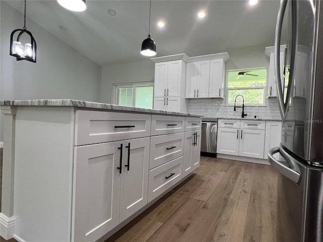 814 Gator Ln, Deltona, FL 32738 - kitchen with stainless steel appliances, backsplash, wood finished floors, white cabinetry, and light stone counters
