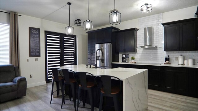 1025 Belvoir Dr, Kissimmee, FL 34744 - kitchen featuring wall chimney exhaust hood, stainless steel fridge, dark cabinets, and light wood-style flooring
