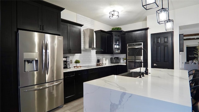1025 Belvoir Dr, Kissimmee, FL 34744 - kitchen with appliances with stainless steel finishes, wall chimney range hood, dark cabinets, and a sink