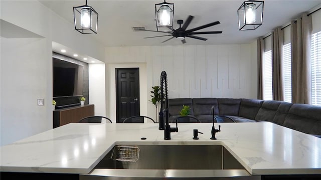 1025 Belvoir Dr, Kissimmee, FL 34744 - kitchen with open floor plan, a sink, a ceiling fan, a center island with sink, and light stone counters