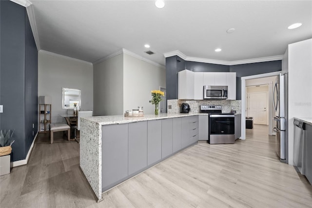 12041 Kajetan Ln, Orlando, FL 32827 - kitchen with stainless steel appliances, a peninsula, light wood-style flooring, light stone countertops, and backsplash