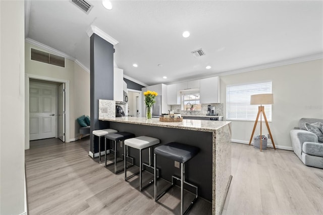 12041 Kajetan Ln, Orlando, FL 32827 - kitchen featuring crown molding, a kitchen breakfast bar, baseboards, white cabinets, and tasteful backsplash