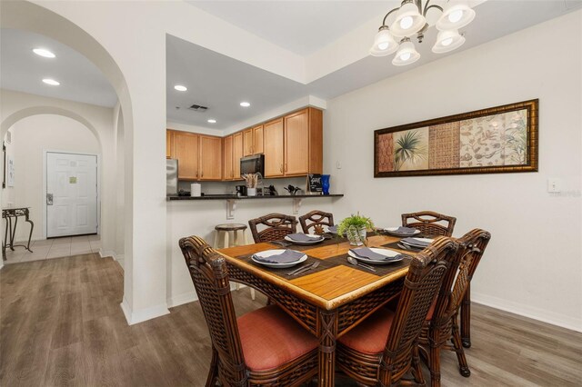 9055 Treasure Trove Ln Unit 409, Kissimmee, FL 34747 - dining space with arched walkways, a chandelier, wood finished floors, baseboards, and recessed lighting