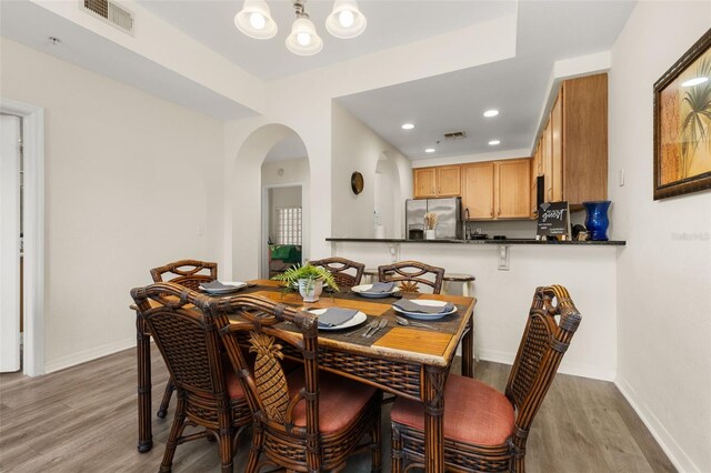 9055 Treasure Trove Ln Unit 409, Kissimmee, FL 34747 - dining space with wood finished floors, arched walkways, a chandelier, recessed lighting, and baseboards