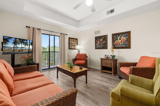 9055 Treasure Trove Ln Unit 409, Kissimmee, FL 34747 - living area featuring a tray ceiling, light wood-style flooring, a ceiling fan, and baseboards