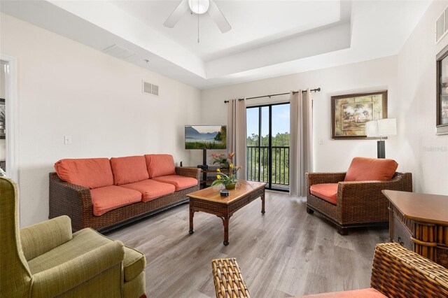 9055 Treasure Trove Ln Unit 409, Kissimmee, FL 34747 - living area with a tray ceiling, a ceiling fan, and light wood-style floors