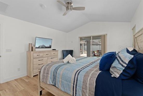 252 Barbera Dr, Davenport, FL 33897 - bedroom with vaulted ceiling, access to exterior, light wood-style flooring, baseboards, and ceiling fan