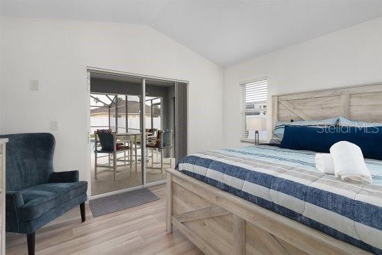 252 Barbera Dr, Davenport, FL 33897 - bedroom featuring access to exterior, vaulted ceiling, and light wood finished floors