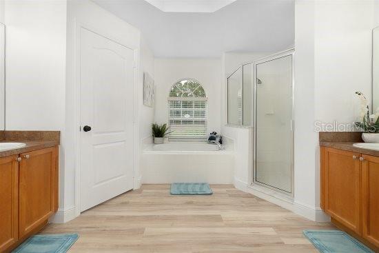 252 Barbera Dr, Davenport, FL 33897 - full bathroom featuring a shower stall, vanity, a bath, and wood finished floors