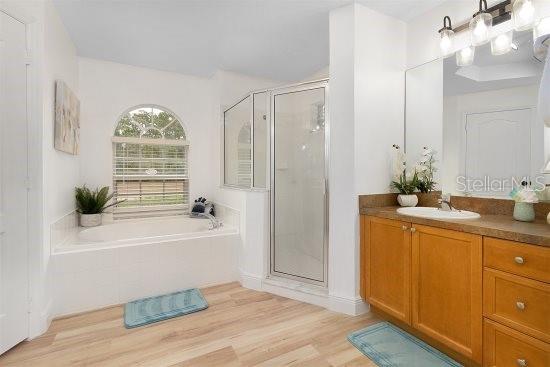 252 Barbera Dr, Davenport, FL 33897 - full bath featuring a stall shower, a bath, vanity, and wood finished floors