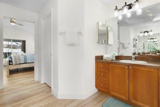 252 Barbera Dr, Davenport, FL 33897 - bathroom with wood finished floors, connected bathroom, ceiling fan, vanity, and baseboards