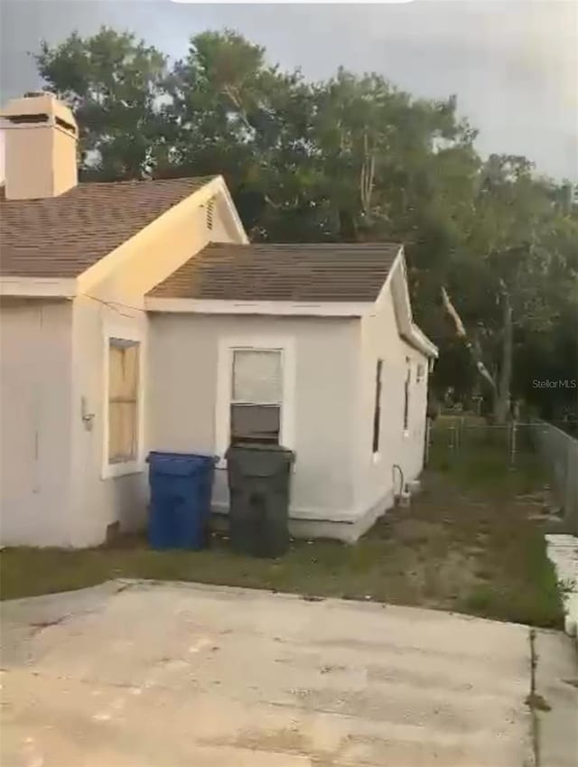 380 S Echo Dr, Lake Alfred, FL 33850 - view of side of property featuring a chimney, roof with shingles, and stucco siding