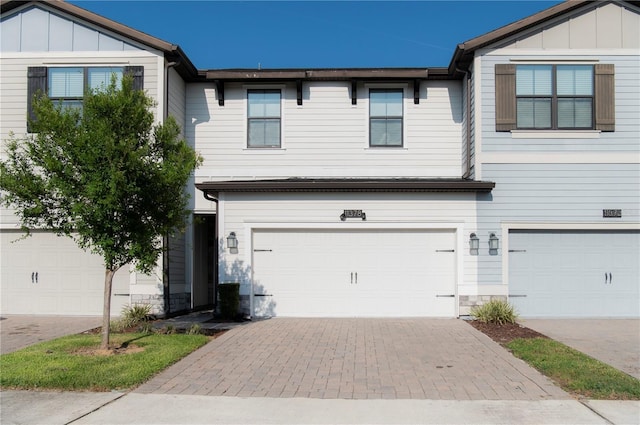11378 Whistling Pine Way, Orlando, FL 32832 - view of front of house with board and batten siding, a garage, stone siding, and driveway