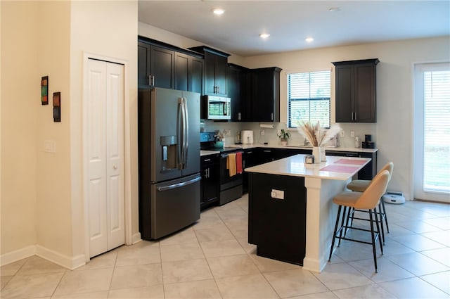 11378 Whistling Pine Way, Orlando, FL 32832 - kitchen featuring appliances with stainless steel finishes, a kitchen breakfast bar, light countertops, a kitchen island, and light tile patterned flooring