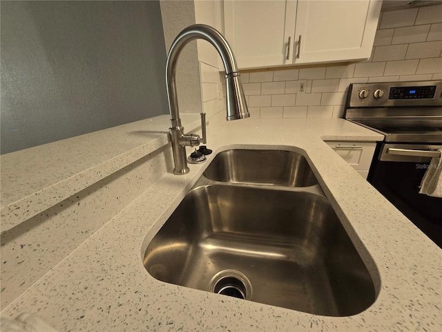 2572 Robert Trent Jones Dr Unit 1227, Orlando, FL 32835 - kitchen view of a sink, stainless steel range with electric cooktop, decorative backsplash, white cabinetry, and light stone counters
