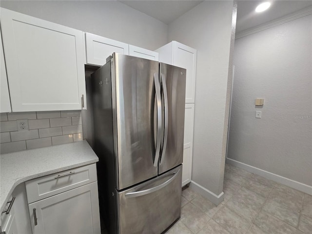 2572 Robert Trent Jones Dr Unit 1227, Orlando, FL 32835 - kitchen with freestanding refrigerator, decorative backsplash, white cabinets, baseboards, and light stone countertops