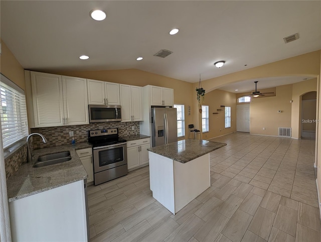 13940 Corrine Key Pl, Orlando, FL 32824 - kitchen featuring appliances with stainless steel finishes, a sink, arched walkways, decorative backsplash, and a kitchen island