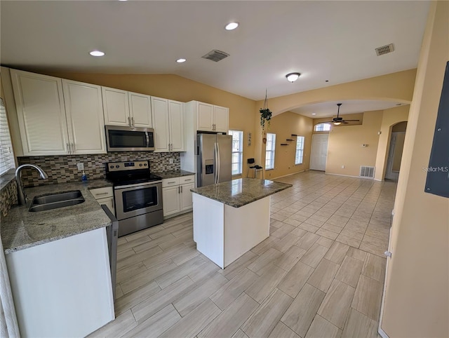 13940 Corrine Key Pl, Orlando, FL 32824 - kitchen featuring appliances with stainless steel finishes, a sink, arched walkways, a center island, and tasteful backsplash