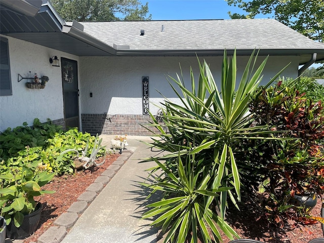 4926 Reginald Rd, Orlando, FL 32829 - property entrance with roof with shingles, stucco siding, and brick siding