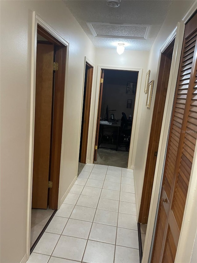 4926 Reginald Rd, Orlando, FL 32829 - hall with light tile patterned flooring, a textured ceiling, and attic access
