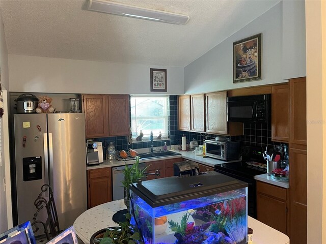 4926 Reginald Rd, Orlando, FL 32829 - kitchen with black appliances, a sink, lofted ceiling, light countertops, and backsplash