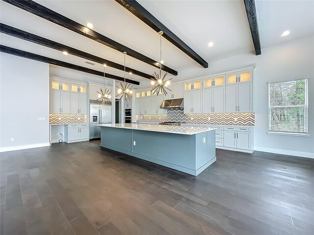 15121 Pendio Dr, Montverde, FL 34756 - kitchen with stainless steel built in fridge, under cabinet range hood, baseboards, light countertops, and a large island with sink