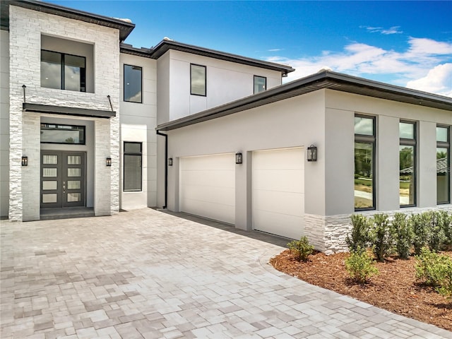 15121 Pendio Dr, Montverde, FL 34756 - contemporary home with stucco siding, stone siding, decorative driveway, and an attached garage