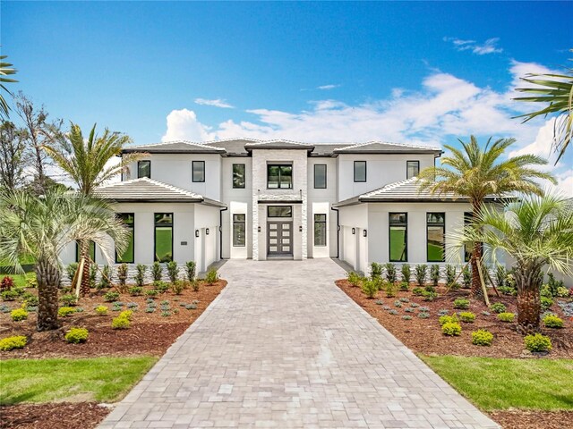 15121 Pendio Dr, Montverde, FL 34756 - view of front facade featuring french doors, decorative driveway, a garage, and a tiled roof