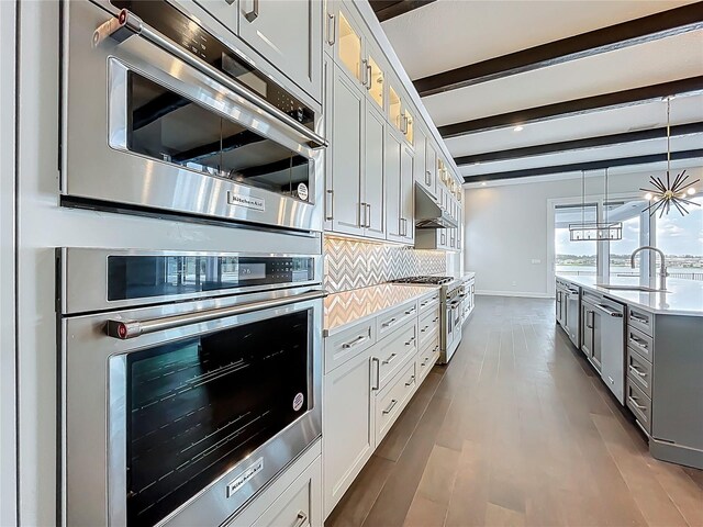 15121 Pendio Dr, Montverde, FL 34756 - kitchen featuring a sink, appliances with stainless steel finishes, beamed ceiling, light countertops, and glass insert cabinets