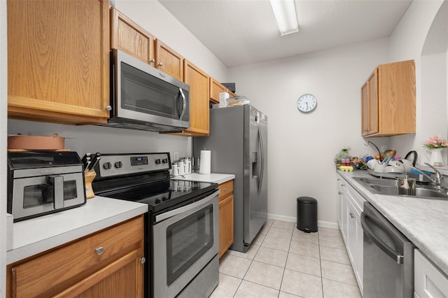 6214 Stevenson Dr Unit 106, Orlando, FL 32835 - kitchen with appliances with stainless steel finishes, a sink, light countertops, light tile patterned floors, and baseboards
